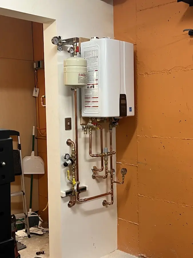 Plumbing technician inspecting water heater connections in Paxton